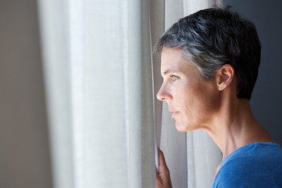 In Frau im mittleren Erwachsenenalter schaut aus dem Fenster. 