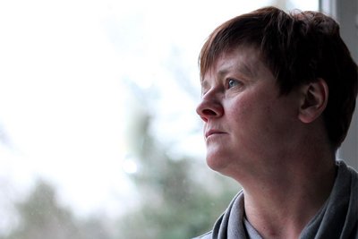 Eine Frau schaut nachdenklich aus dem Fenster. Die Corona-Pandemie führt zu psychischen Belastungen.