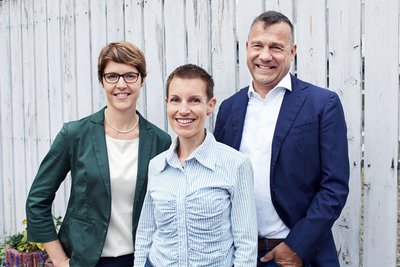  Dr. Tabea Send, Dr. Simona Maltese und Prof. Dr. Michael Deuschle stehen vor einem Zaun. Die drei leiten das Projekt MHFA Ersthelfer. 