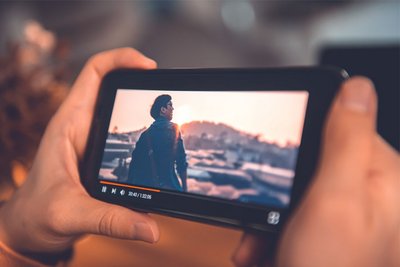 Eine Frau sieht sich zuhause Videos über ihr Smartphone an. 