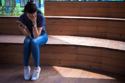 Eine junge Frau ist nach dem Blick auf ihr Smartphone verzweifelt. Die gesundheitlichen Beeinträchtigungen von Stalking-Betroffenen sind erheblich.