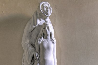 Das Bild zeigt eine Statue mit Antonia Werr, Gründerin der Oberzeller Franziskanerinnen, die ein junges Mädchen beschützend im Arm hält. 