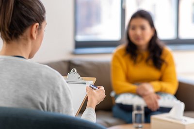 A woman is sitting on a sofa with a psychotherapist.