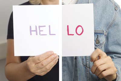 Zwei Patientinnen halten ein Schild in die Höhe auf dem "Hello" geschrieben ist.