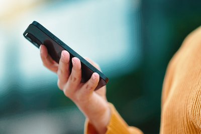Eine Frau hält ein Smartphone in der Hand und wischt über das Display.