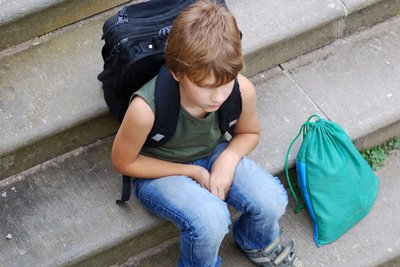 Ein Junge sitzt auf einer Treppe. Kinder psychisch Erkrankter benötigen Unterstützung.