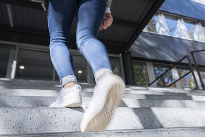 Eine Frau steigt die Treppe hinauf, um in eine Gebäude zu gelangen. 