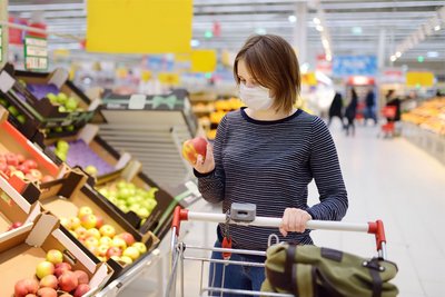 Eine Frau kauft im Supermarkt während der Corona-Pandemie mit Maske ein.