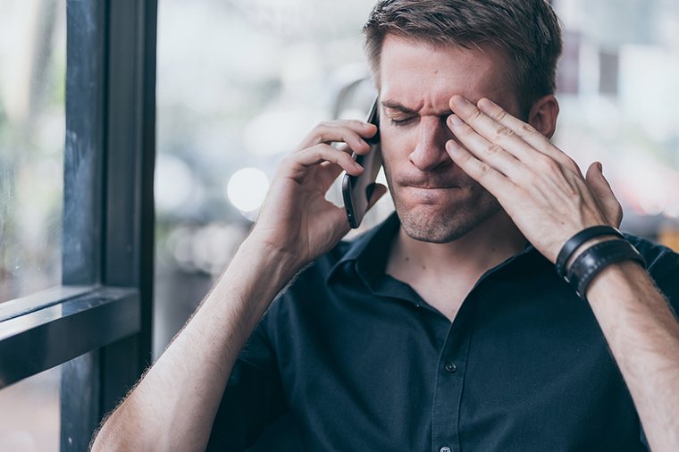 Ein junger Mann hält ein Smartphone in der Hand und wirkt frustriert. 