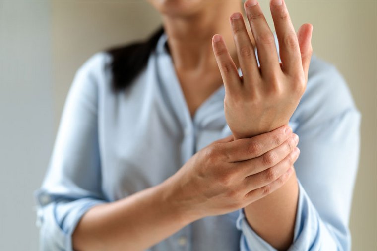 Eine Frau hält sich vor Schmerz das Handgelenk. Für unsere Studie suchen wir PatientInnen mit chronischen Schmerzen.