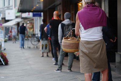 Menschen stehen mit Sicherheitsabstand an, um beim Bäcker einzukaufen.