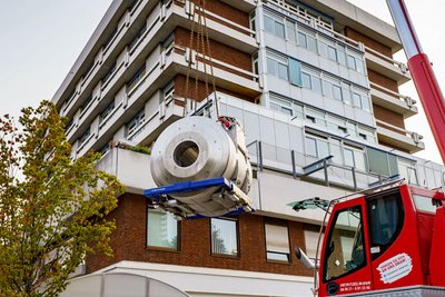 Ein Kran hält das rund 20 Tonnen schwere 7-Tesla-MRT in der Luft, bevor es ins  Therapiegebäude abgelassen wird.