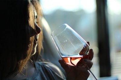 Eine Frau sitzt an einem Fenster und möchte gerade an einem Weinglas trinken. 