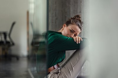 Eine junge Frau sitzt verzweifelt im Büro.