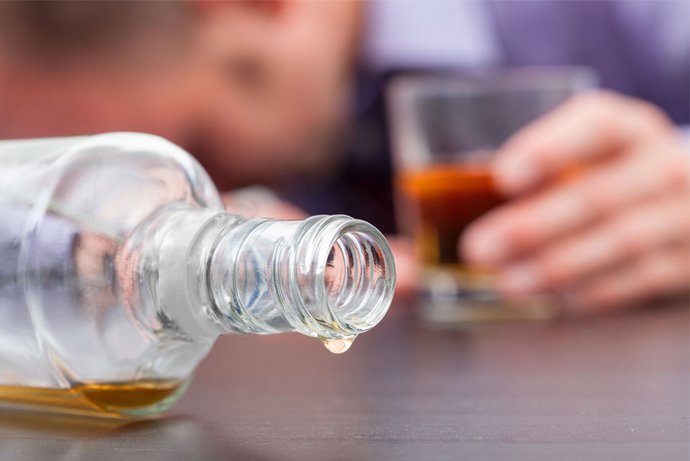 Ein Mann hat eine Flasche Alkohol geleert. 