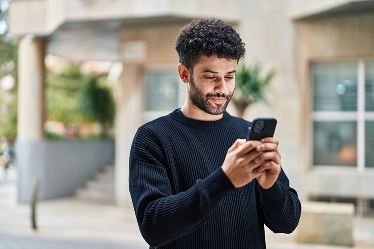 Ein junger Mann an seinem Smartphone. 