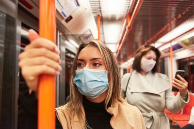 Eine junge Frau steht in der S-Bahn mit einer Maske vor dem Gesicht. Im Digi-PEZ Projekt untersucht das ZI, wie sich das Wohlbefinden der Menschen in der Pandemie verändert. 