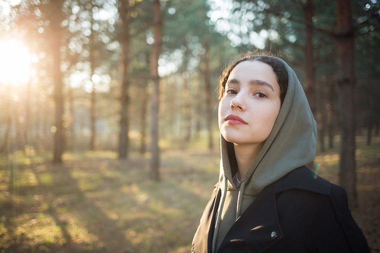 Eine junge Frau ist einem auf einer sonnigen Lichtung in einem Wald.