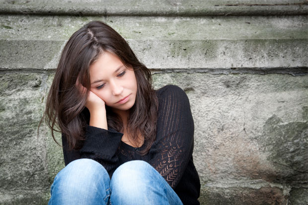 Eine Frau mit chronischer Depression sitzt vor einem Gebäude. Die CBASP-Therapie am ZI in Mannheim kann hier helfen.