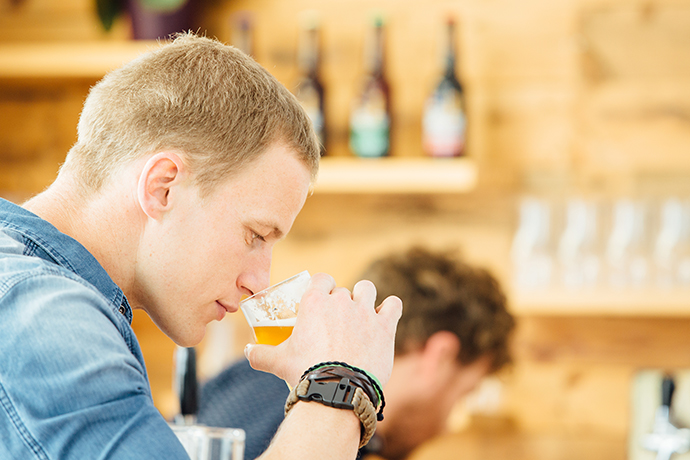 Ein junger Mann riecht an seinem Bier. 
