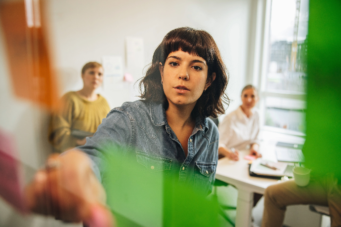 Frau in einem Meeting klebt ein Postet an eine Glasscheibe.
